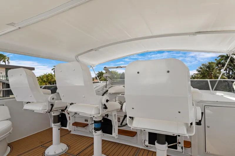 Slide: The Image of Three white captain chairs on a 1985 Burger yacht deck under a canopy. - 38