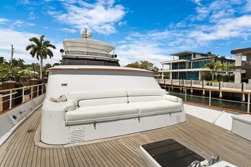 Slide: The Image of Luxury yacht deck with white seating, docked near modern waterfront homes, under a clear blue sky. - 44