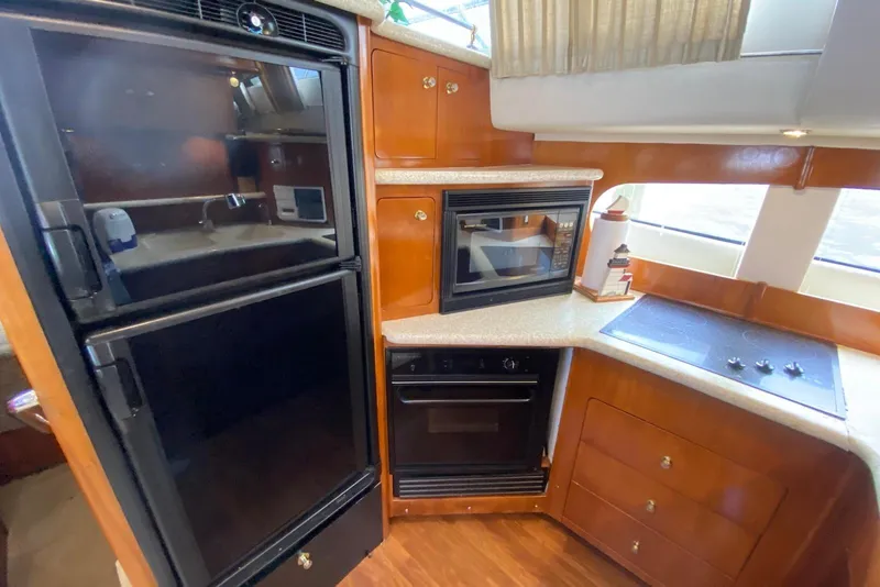 Slide: The Image of Kitchen area of a 2000 Carver 506 Motor Yacht with appliances and wood cabinetry. - 22