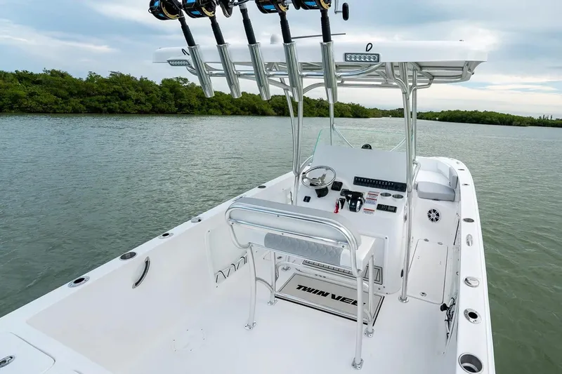 Slide: The Image of Manufacturer Provided Image: 2026 Twin Vee 240 STX CC boat interior with fishing rod holders on a calm lake. - 10