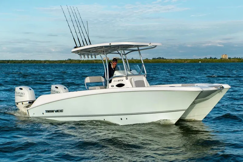 Slide: The Image of Manufacturer Provided Image: 2026 Twin Vee 240 STX CC boat cruising on open water with dual Suzuki engines. - 2