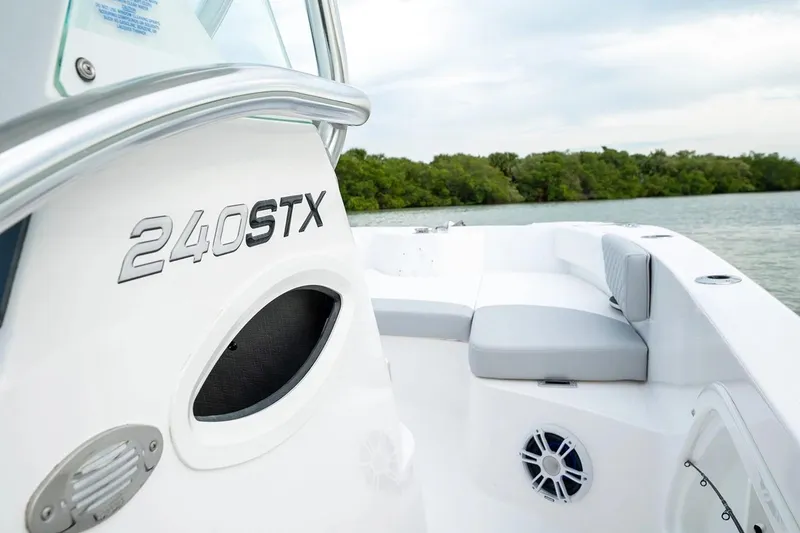 Slide: The Image of Manufacturer Provided Image: 2026 Twin Vee 240 STX CC boat interior with seating, near water and greenery. - 6