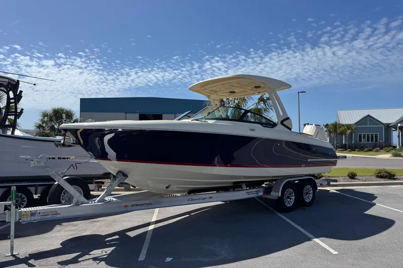 The Image of 2026 Chris-Craft Sportster 28 boat on trailer, parked outdoors under clear sky. - 1
