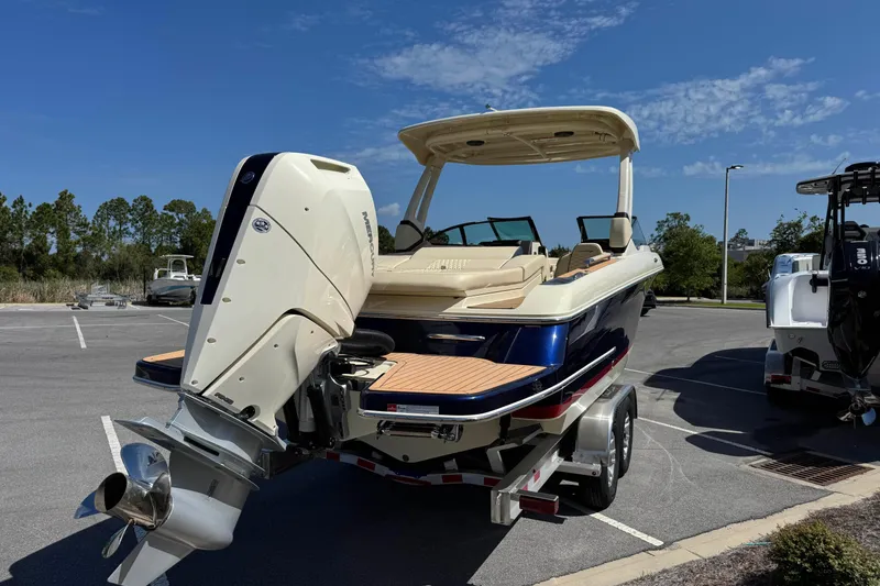 Slide: The Image of 2026 Chris-Craft Sportster 28 boat on trailer, parked outdoors under clear blue sky. - 4