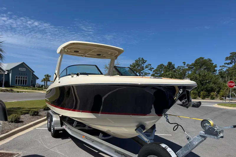 Slide: The Image of 2026 Chris-Craft Sportster 28 boat on trailer, parked near a road with clear blue sky. - 6