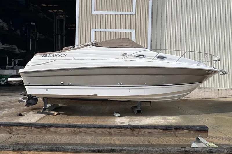 The Image of 2006 Larson Cabrio 260 boat on dry dock, beige and white exterior. - 0