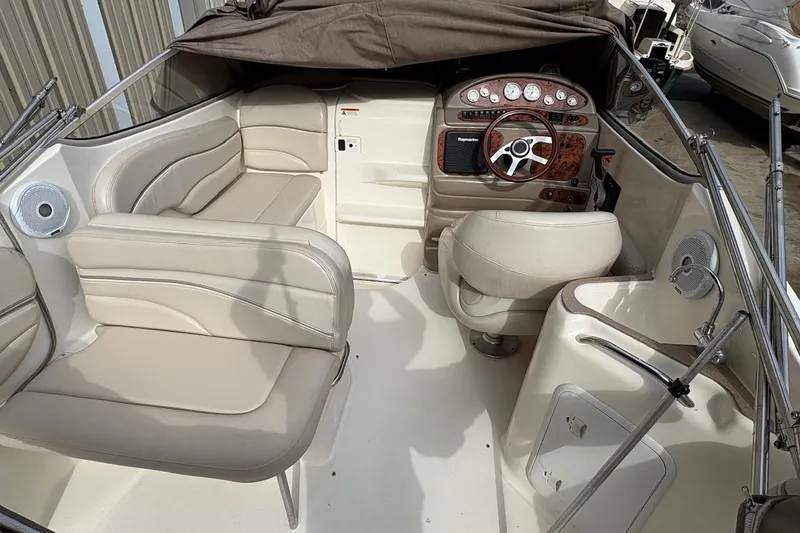 Slide: The Image of 2006 Larson Cabrio 260 boat interior with beige seating and wood-accented dashboard. - 12