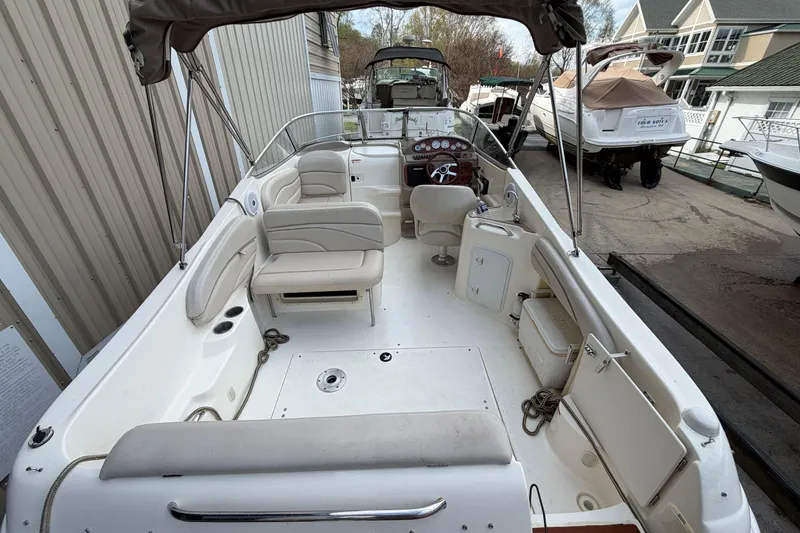 Slide: The Image of 2006 Larson Cabrio 260 boat interior with seating and steering wheel, docked outdoors. - 17