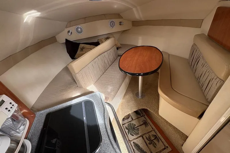 Slide: The Image of 2006 Larson Cabrio 260 cabin interior with cozy seating and wooden table. - 7