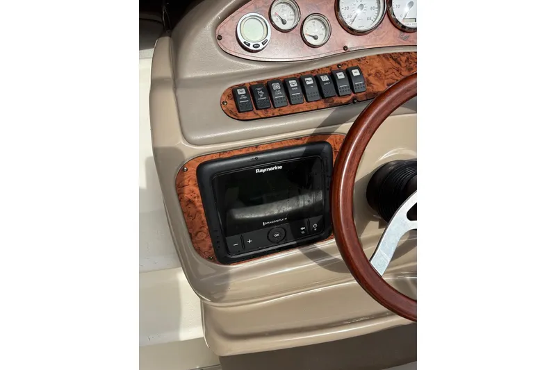 Slide: The Image of 2006 Larson Cabrio 260 dashboard with Raymarine navigation system and wood-trimmed steering wheel. - 8