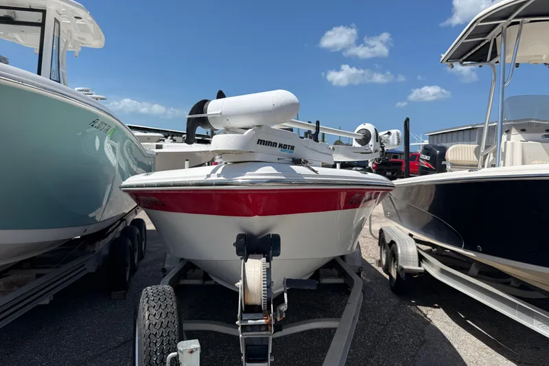 The Image of 2010 Sea Hunt XP 19 boat on trailer, parked between two other boats. - 0