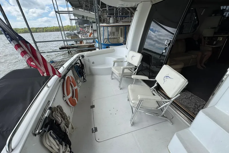 Slide: The Image of 1999 Carver 450 Voyager Pilothouse yacht deck with chairs and American flag. - 12