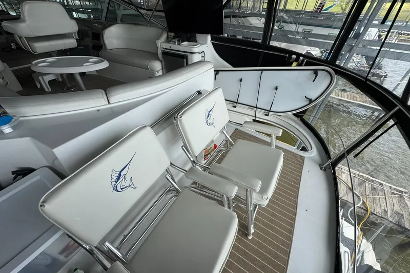 Slide: The Image of Interior of 1999 Carver 450 Voyager Pilothouse with white seating and marlin logo. - 15