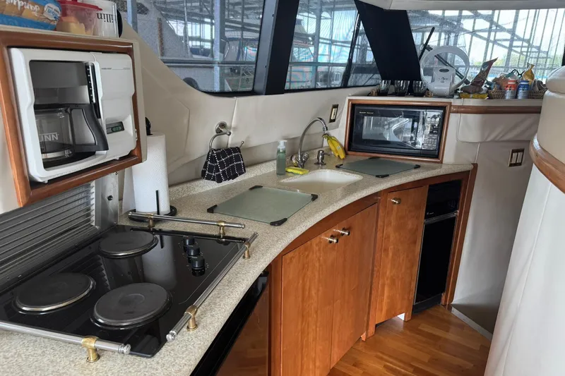 Slide: The Image of 1999 Carver 450 Voyager Pilothouse kitchen with stove, microwave, and sink. - 31