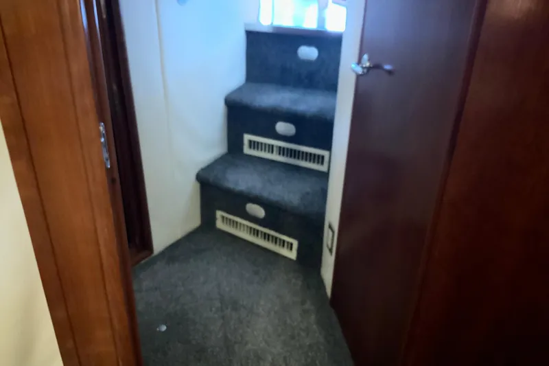 Slide: The Image of Carpeted stairs inside 1999 Carver 450 Voyager Pilothouse yacht, featuring wooden doors. - 50