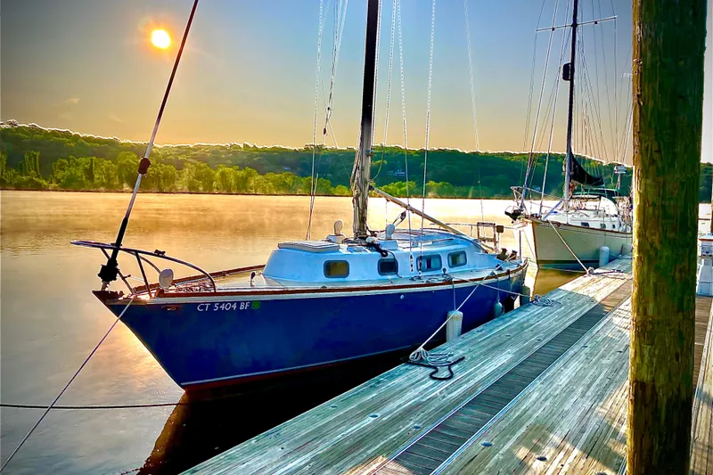The Image of 1974 Tartan Sloop sailboat docked at sunset, reflecting on calm water. - 0