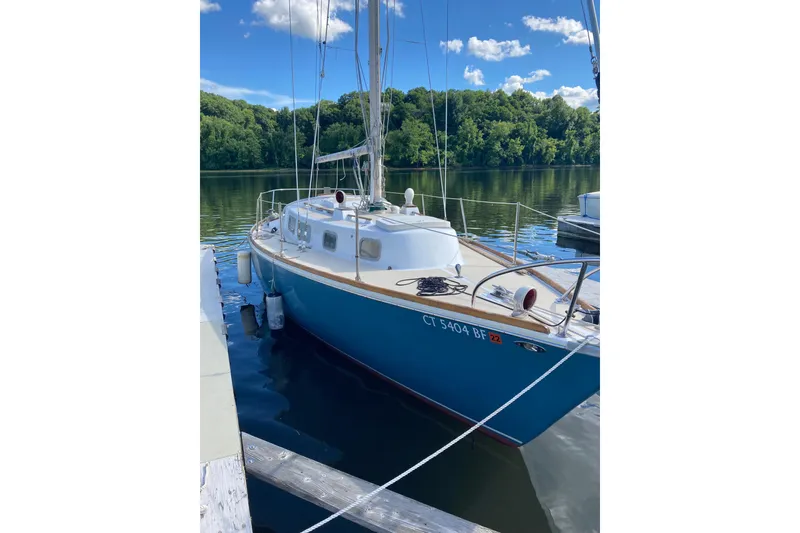 Slide: The Image of 1974 Tartan Sloop sailboat docked on a serene lake with lush green trees. - 5