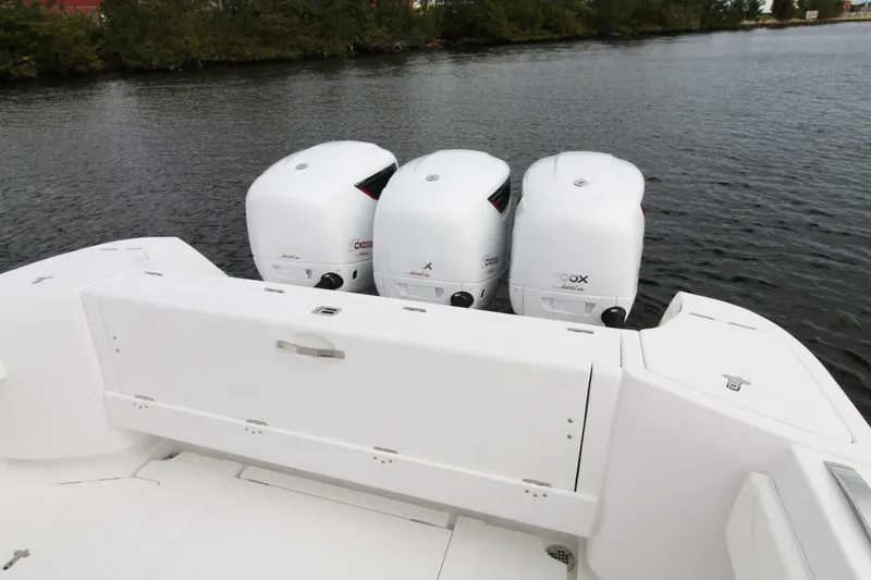 Slide: The Image of 2024 Intrepid 375 Nomad SE boat with triple outboard engines on calm water. - 2