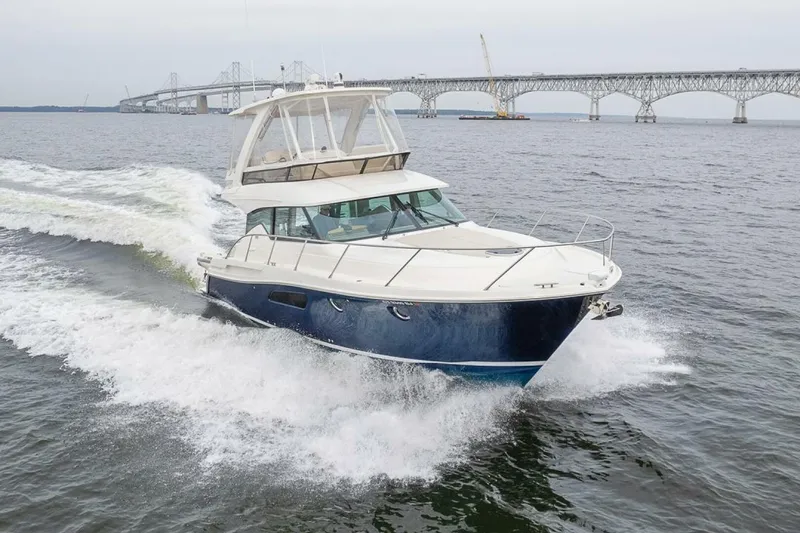 Slide: The Image of 2021 Tiara Yachts F44 Flybridge cruising near a bridge on open water. - 2