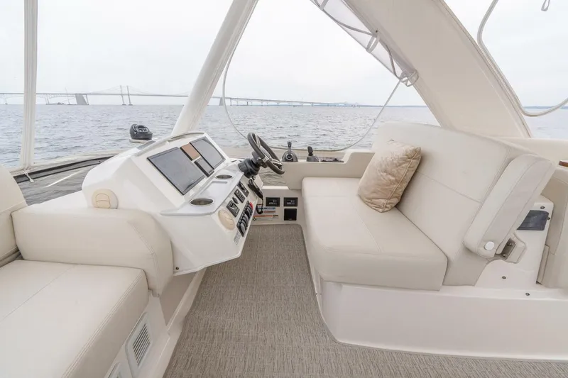 Slide: The Image of 2021 Tiara Yachts F44 Flybridge interior with helm and seating, overlooking water and bridge. - 50