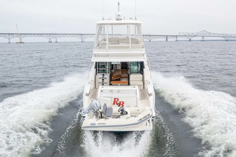 Slide: The Image of 2021 Tiara Yachts F44 Flybridge cruising on open water near a bridge. - 7