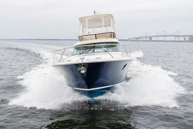 Slide: The Image of 2021 Tiara Yachts F44 Flybridge cruising on open water near a bridge. - 8