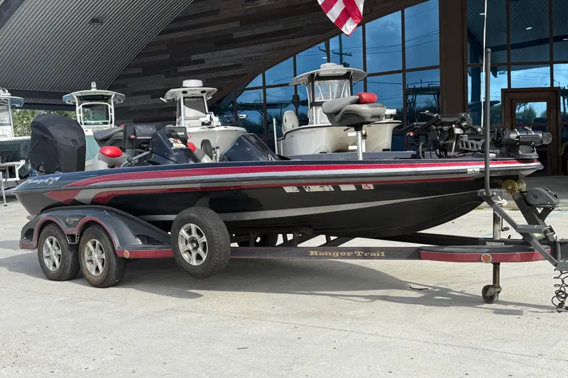 Slide: The Image of 2011 Ranger 521SVX Comanche boat on trailer, parked outdoors near other boats. - 2