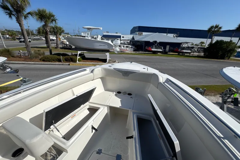 Slide: The Image of 2026 Sailfish 272 CC boat interior with open storage compartments, docked near palm trees. - 19
