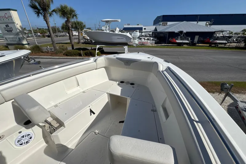 Slide: The Image of 2026 Sailfish 272 CC boat interior with seating and storage, displayed outdoors at a marina. - 20
