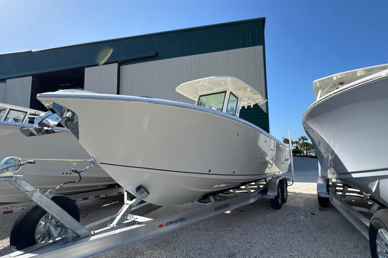 Slide: The Image of 2026 Sailfish 272 CC boat on trailer, parked outdoors under clear blue sky. - 6