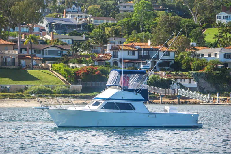 Slide: The Image of 1996 Blackman Sportfisher 32 yacht on calm water near coastal homes. - 2