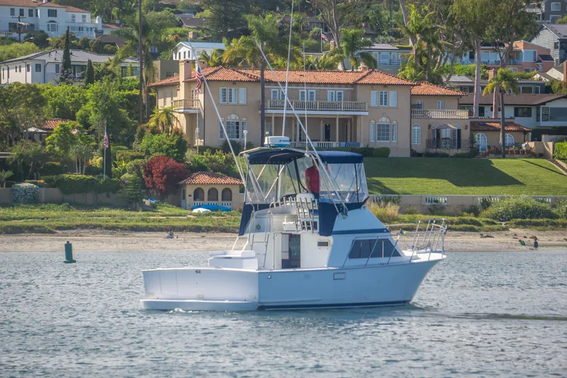 Slide: The Image of 1996 Blackman Sportfisher 32 boat cruising near luxurious waterfront homes. - 3
