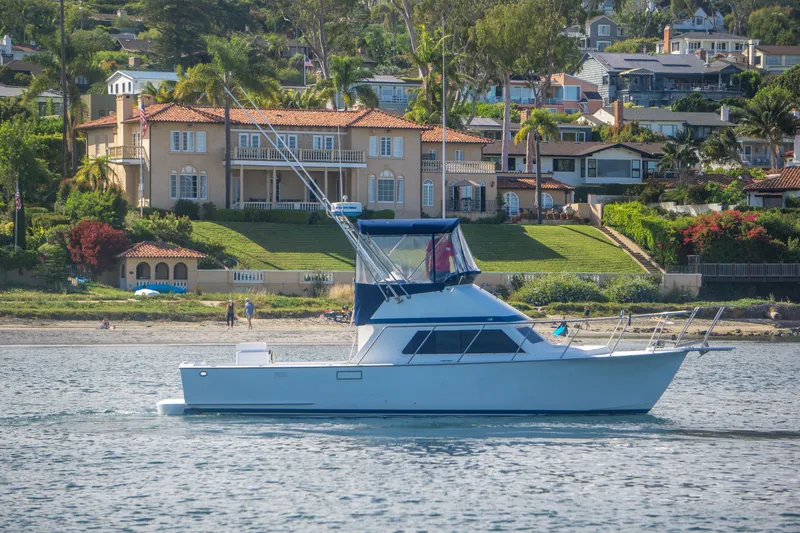Slide: The Image of 1996 Blackman Sportfisher 32 yacht cruising near luxurious waterfront homes. - 4