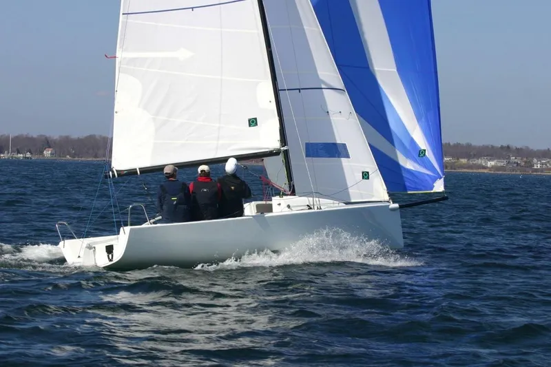 The Image of 2013 J Boats J/70 sailing on open water with crew, featuring blue and white sails. - 2