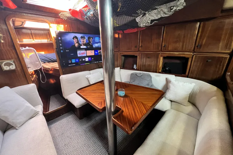 Slide: The Image of Cozy 1985 Pinical 14-34 yacht interior with TV, wooden table, and cushioned seating. - 13