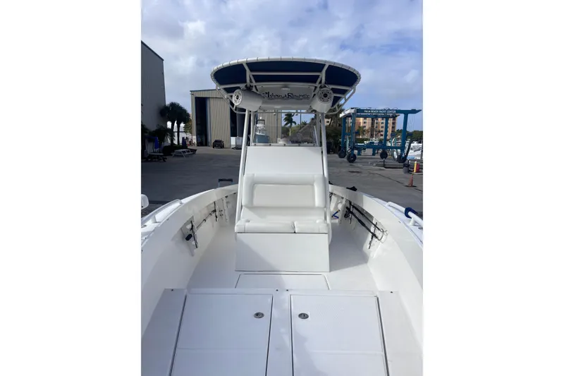 Slide: The Image of 2003 Island Runner 26 Center Console boat with white seating and blue canopy in marina. - 9