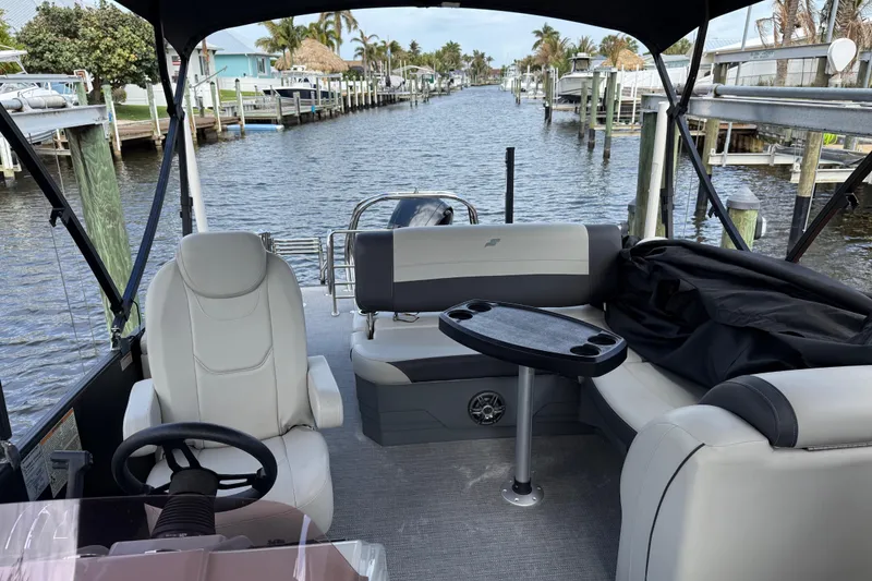 The Image of 2023 Starcraft EXS 3 Q pontoon boat interior with seating and table on a canal. - 0