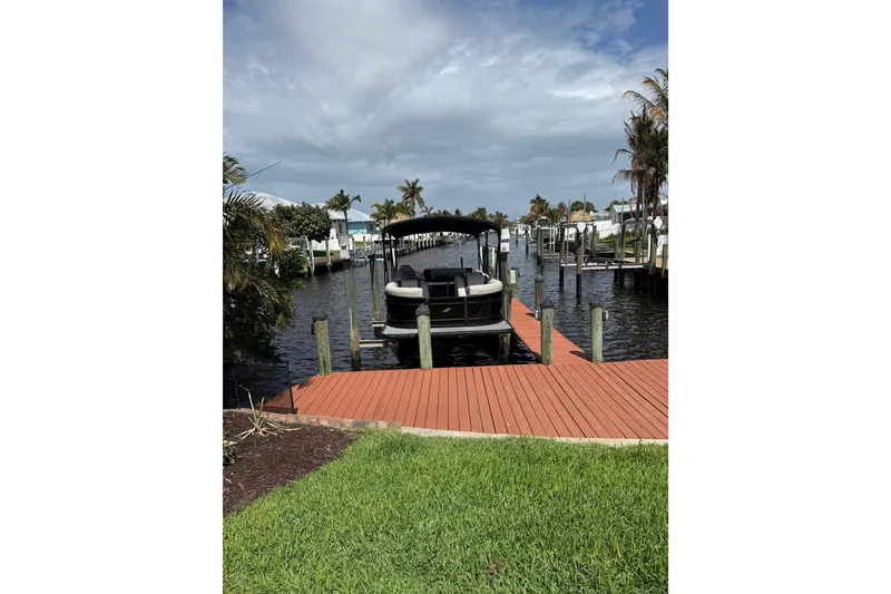 Slide: The Image of 2023 Starcraft EXS 3 Q boat docked on a sunny waterfront with palm trees. - 16