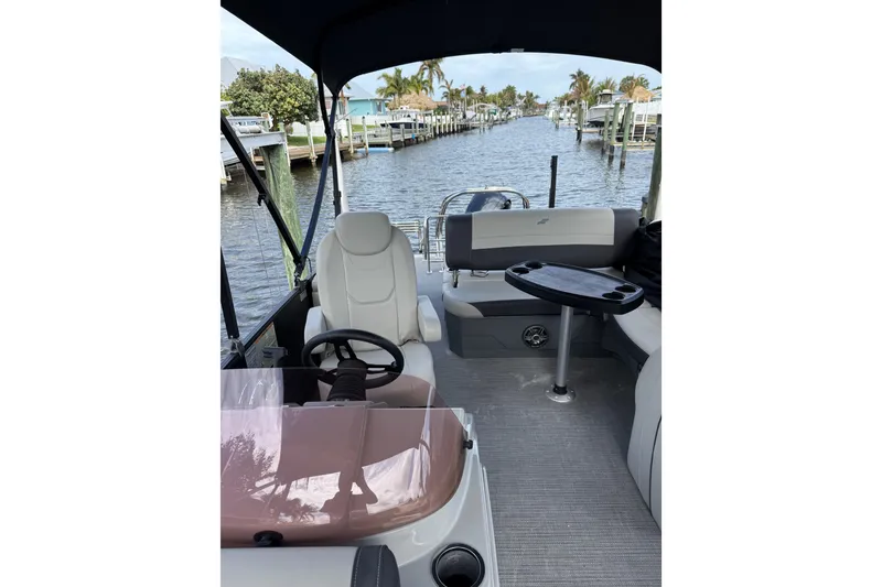 Slide: The Image of 2023 Starcraft EXS 3 Q boat interior with helm, seating, and table on a scenic waterway. - 6