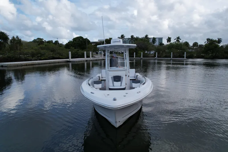 Slide: The Image of 2021 Robalo R230 Center Console boat on calm water, surrounded by lush greenery. - 10