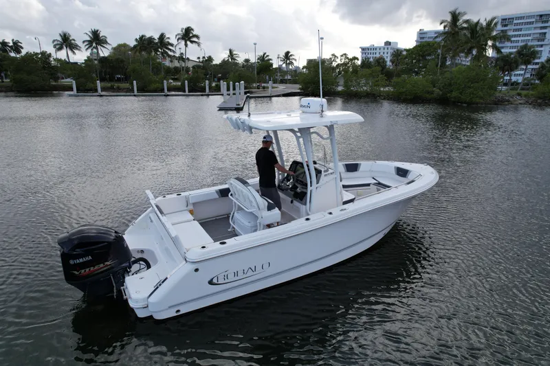 Slide: The Image of 2021 Robalo R230 Center Console boat on calm water, surrounded by palm trees. - 16