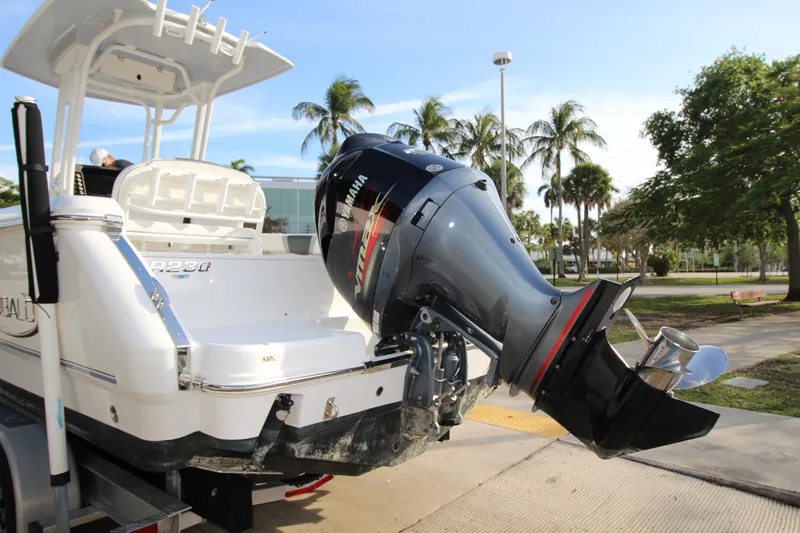 Slide: The Image of 2021 Robalo R230 Center Console boat with Yamaha outboard motor, parked near palm trees. - 17