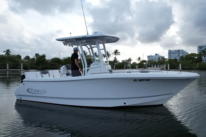 Slide: The Image of 2021 Robalo R230 Center Console boat on calm water, cloudy sky background. - 2