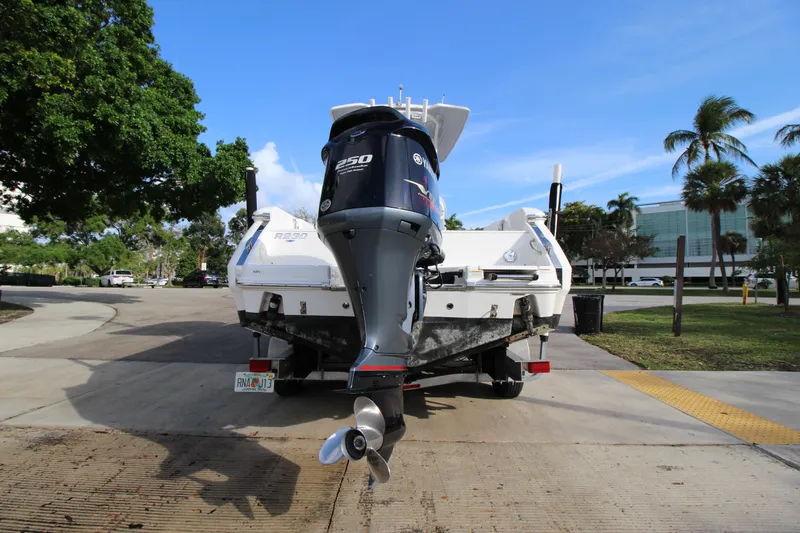 Slide: The Image of 2021 Robalo R230 Center Console boat on trailer, parked outdoors with trees and buildings. - 21