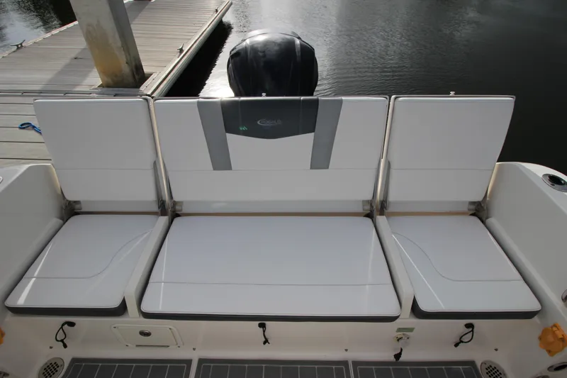 Slide: The Image of 2021 Robalo R230 Center Console boat seating at dockside, featuring cushioned seats and motor. - 26