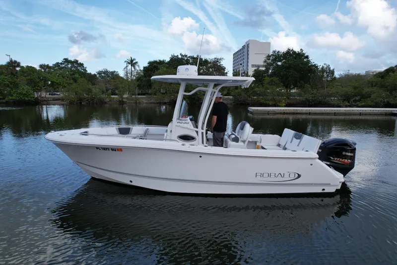 Slide: The Image of 2021 Robalo R230 Center Console boat on calm water, featuring sleek design and Yamaha outboard motor. - 4