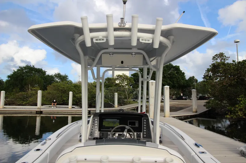 Slide: The Image of 2021 Robalo R230 Center Console boat docked, featuring helm and T-top under a cloudy sky. - 43