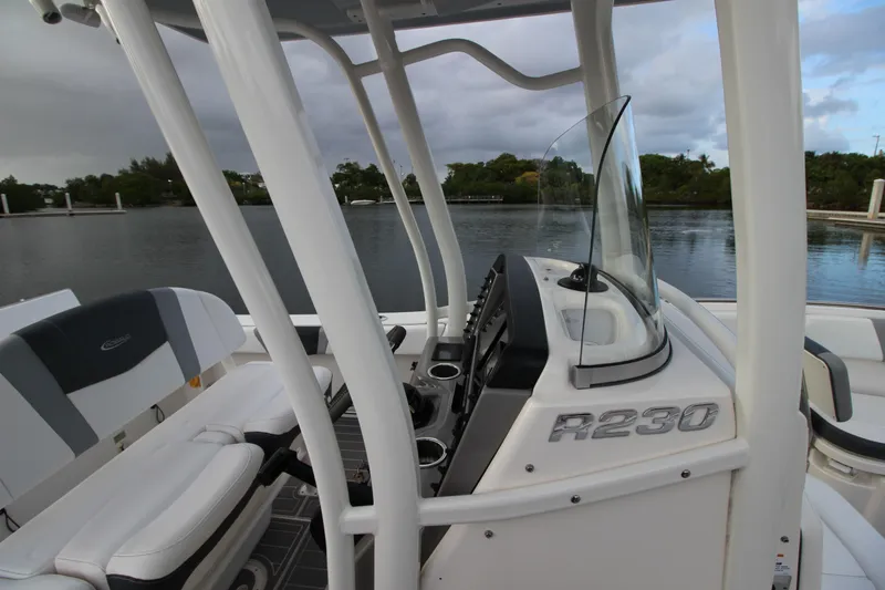 Slide: The Image of 2021 Robalo R230 Center Console boat interior with helm and seating by the water. - 60