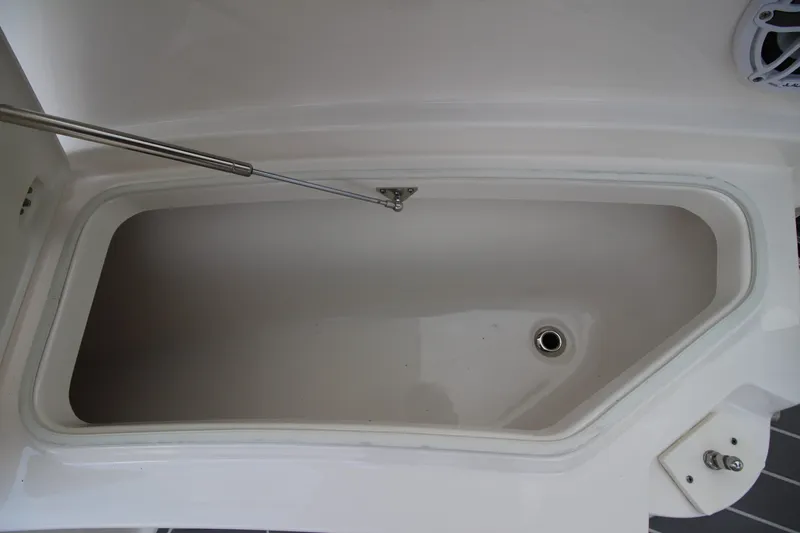 Slide: The Image of 2021 Robalo R230 Center Console storage compartment with open lid and drainage. - 75