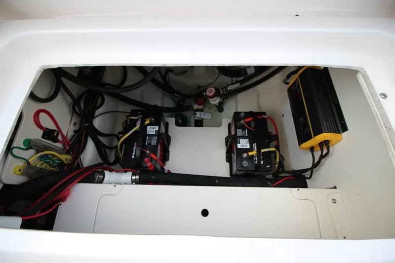 Slide: The Image of 2021 Robalo R230 Center Console boat battery compartment with wiring and charger. - 78